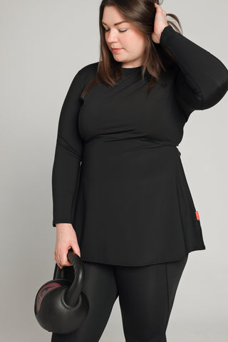 Well Fit Activewear. Female model wears long sleeve black compression gym top in a longer length tunic style and black compression leggings to the ankle. Well Fit tops and leggings are available in UK sizes 8 to 30. Free shipping over £100.