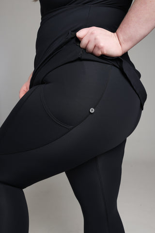 Grace, model, plus size 20 UK, wears Well Fit Connex range. In this images, Grace demonstrates the button fastening on the leggings where the tunic-style gym top attaches.