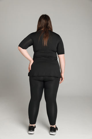 Well Fit Activewear. Female model wears black, lightweight, short sleeve, tunic-style gym top with black gym leggings. Well Fit tops and leggings are available in UK sizes 8 to 30. Free shipping over £100.