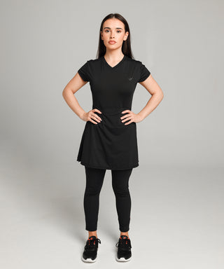 Well Fit Activewear. Female model wears black, lightweight, tunic-style gym top with black gym leggings. Well Fit tops and leggings are available in UK sizes 8 to 30. Free shipping over £100. Model, Jasmine, is 5 foot tall and stands facing the camera with both hands on hips.