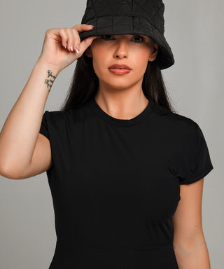 Well Fit Activewear. Female model wears black compression gym top in a longer length tunic style. Well Fit tops and leggings are available in UK sizes 8 to 30. Free shipping over £100. Model, Jasmine, wears a black bucket hat.